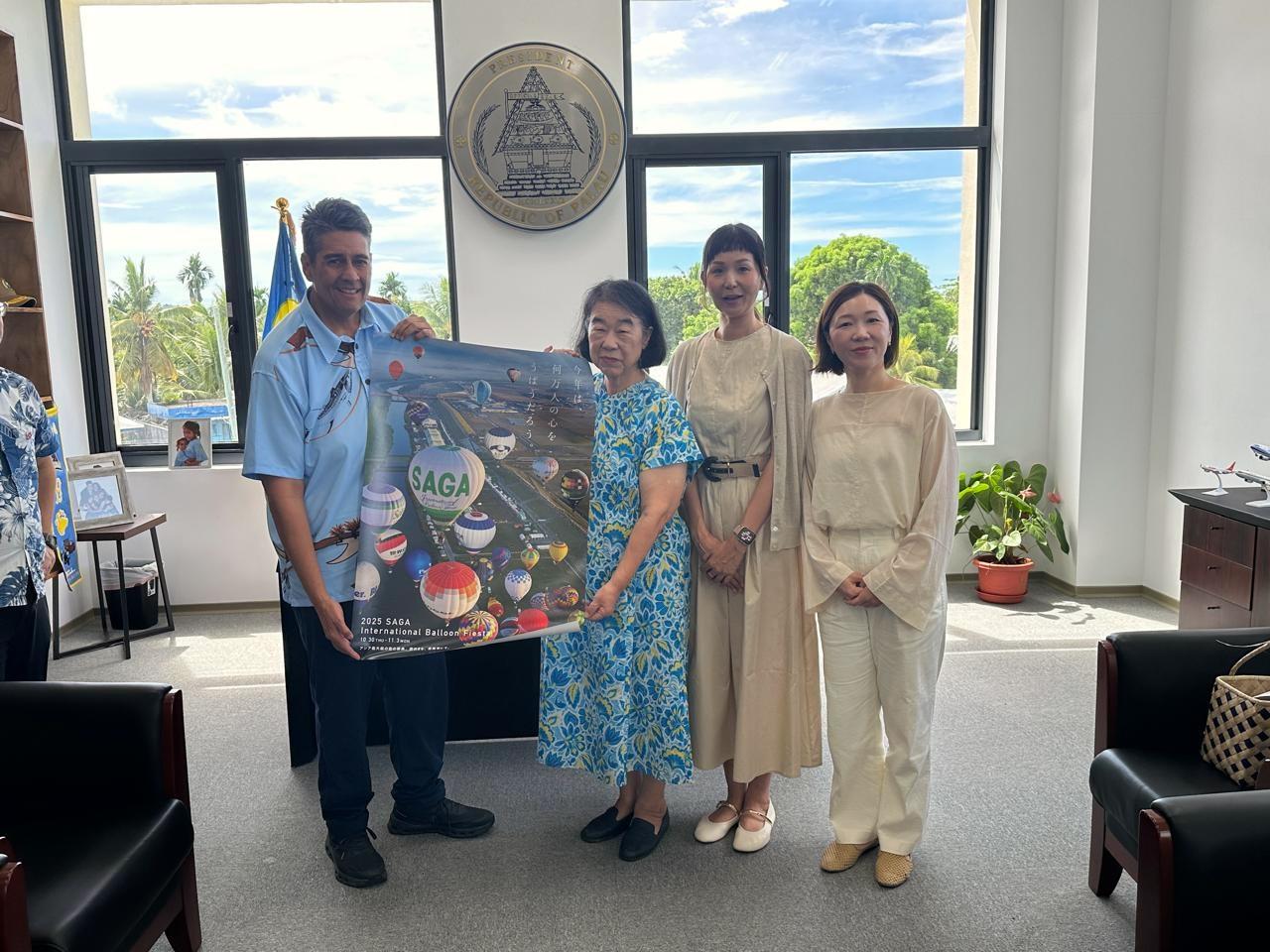 Atsuko Tateshita, representing non-profit organization Ai Mirai, presented a poster of the upcoming 2025 Saga International Balloon Fiesta to President Surangel S. Whipps, Jr. 